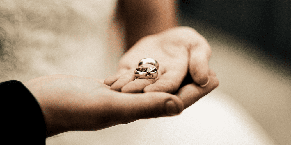 Bride and Groom at Wedding Holding Hands with Restored Wedding Bands and Engagement Ring in Palms